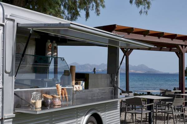 Eis-Mobil am Strand vor dem Atlantica Beach Resort Kos mit Eisbechern und Tisch.