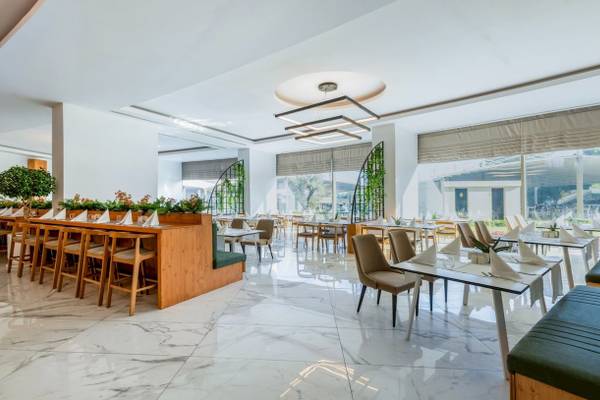 Ein modernes Restaurant mit weißen Wänden, Marmorböden und großen Fenstern im Nirvana Cosmopolitan Hotel.