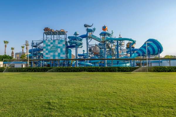 Wasserpark Aqua Atlantis mit großen blauen Rutschen und grüner Rasenfläche
