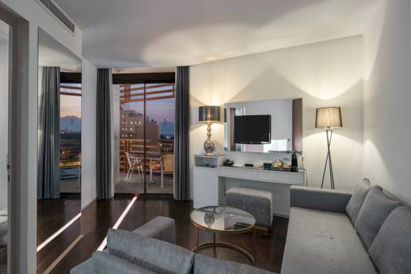 Hotelzimmer im Nirvana Cosmopolitan mit Balkon, Fernseher, Couch und Schreibtisch.
