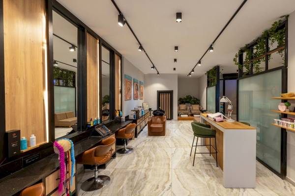 Innenansicht des Nirvana Cosmopolitan Hotels mit Friseursalon, Spiegeln, Stühlen und Empfangstresen.