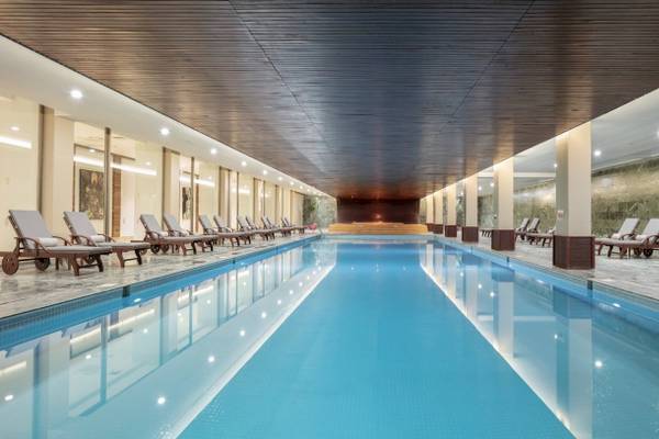 Innenpool des Nirvana Cosmopolitan Hotels mit Liegen und beleuchteten Wänden.