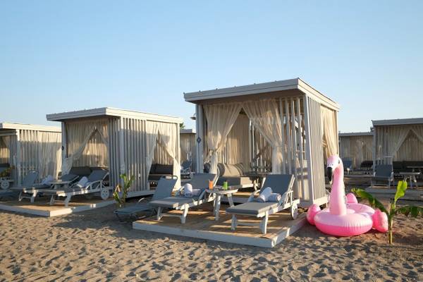 Lounges am Strand des Nirvana Cosmopolitan Hotels mit Flamingo-Pool und Sonnenliegen