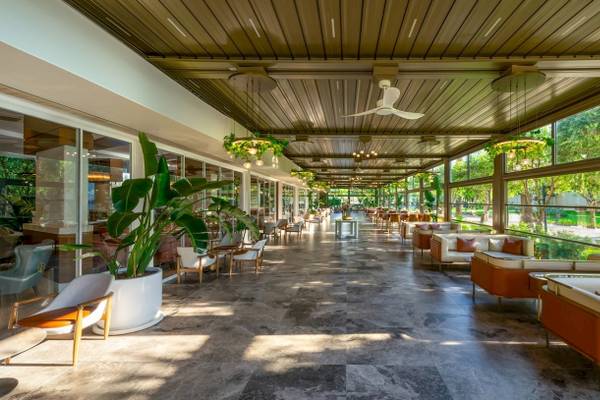 Innenbereich des Nirvana Cosmopolitan Hotels mit Sofas, Tischen, Pflanzen und Deckenventilatoren.