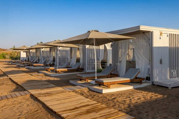 Reihe von Strandlounges mit Sonnenschirmen und Sonnenliegen auf einem Holzsteg