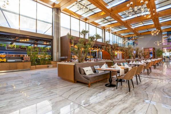 Innenbereich des Nirvana Cosmopolitan Hotels mit gepolsterten Bänken und runden Tischen.