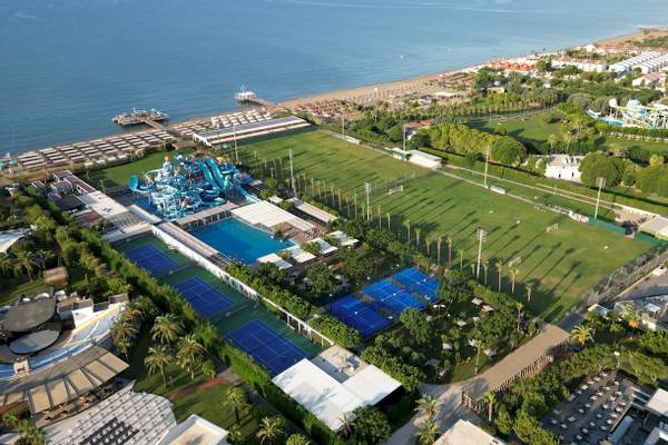 Luftbild des Nirvana Cosmopolitan Hotels mit Wasserrutsche, Tennisplätzen und Meer im Hintergrund.