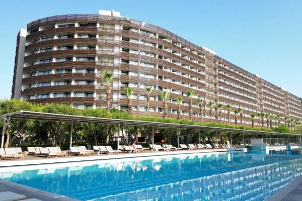 Das Nirvana Cosmopolitan Hotel mit einem großen Swimmingpool und Sonnenliegen davor.