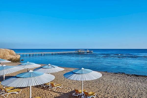 Strand des Jaz Grand Marsa mit Sonnenliegen und Sonnenschirmen, Blick aufs Meer und eine Pier