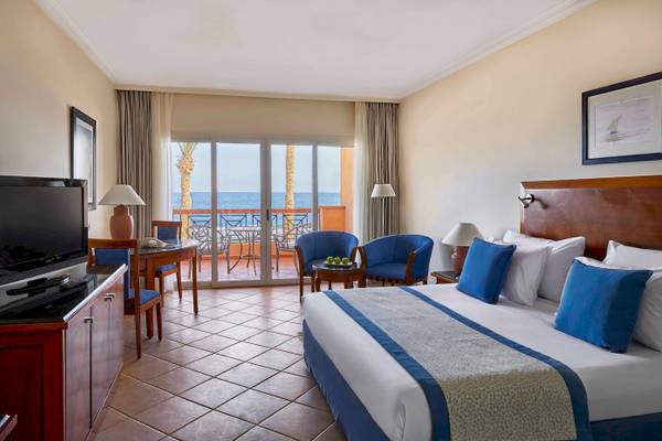Jaz Grand Marsa Hotel Zimmer mit Meerblick und Balkon, ausgestattet mit Fernseher, Tisch und Stühlen.
