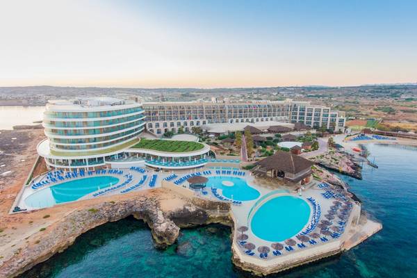 Luftaufnahme des Ramla Bay Resorts mit mehreren Swimmingpools und Sonnenliegen vor der Küste