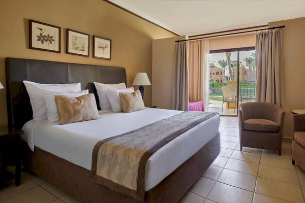 Schlafzimmer im Jaz Lamaya Resort mit Doppelbett, Kissen, Lampen und Zugang zu einer Terrasse.