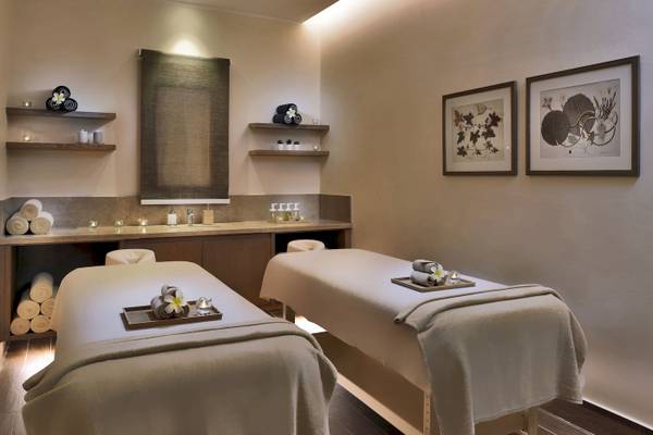 Spa-Behandlungsraum im Jaz Lamaya Resort mit zwei Massagetischen, Kerzen und Pflanzen.