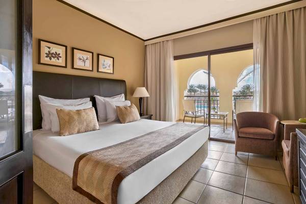 Hotelzimmer im Jaz Lamaya Resort mit bequemem Bett und gemütlichem Balkonzugang.