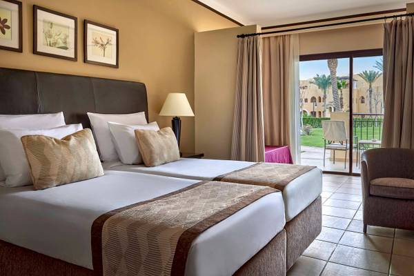 Doppelzimmer im Jaz Lamaya Resort mit zwei Betten, Lampe, Sessel und Balkon.