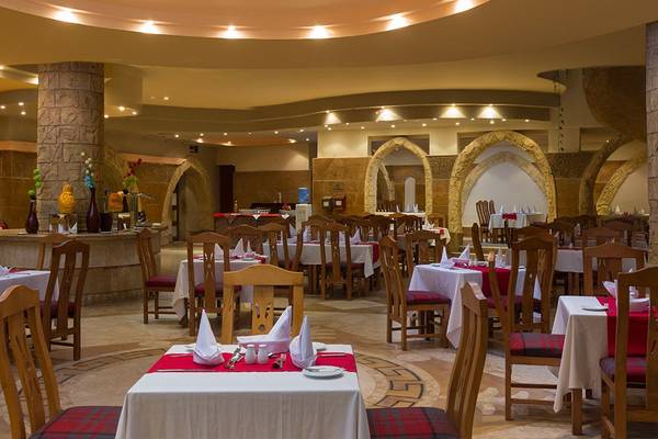 Innenansicht des Restaurants im Utopia Beach Club mit runden Tischen und Stühlen, dekorierten Tischen und architektonischen Bögen.