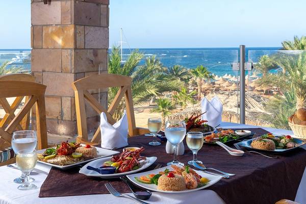 Utopia Beach Club mit Blick auf das Meer und einer servierten Mahlzeit auf dem Tisch.