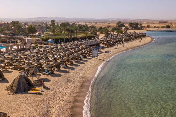 Luftaufnahme des Utopia Beach Club Strands mit vielen Sonnenschirmen und Hotelgebäuden