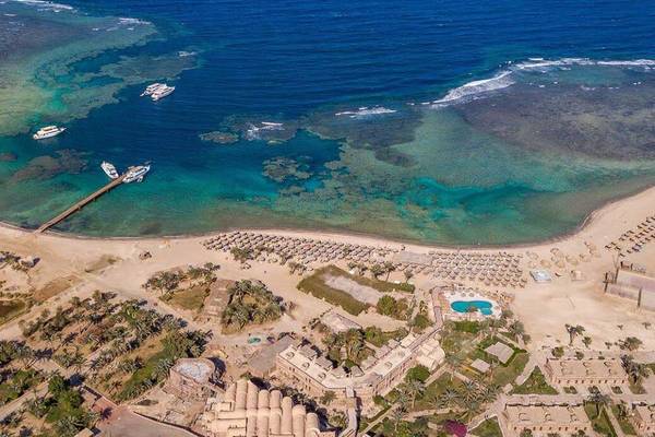 Utopia Beach Club Außenansicht mit Strand, Meer und Gebäuden.