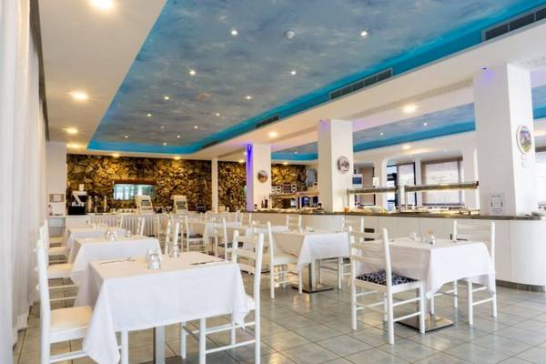 Innenbereich des Anonymous Beach Hotels mit blauem Himmel-Decke, weißen Tischen und Stühlen.