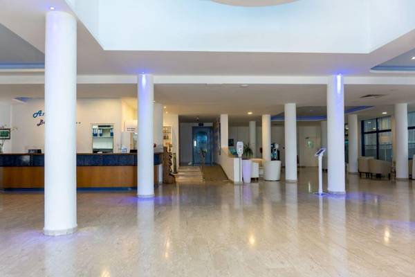 Lobby des Anonymous Beach Hotels mit Empfangstresen, weißen Säulen und Sitzbereich.