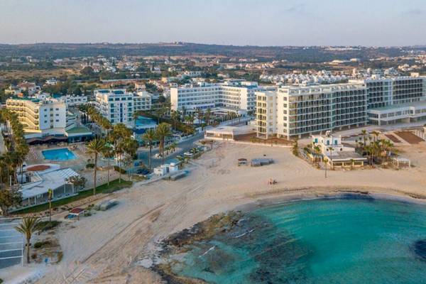 Luftaufnahme des Anonymous Beach Hotels mit mehreren Gebäuden, einem Pool und einer breiten Sandbucht.