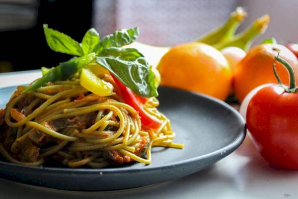 Spaghetti-Gericht mit Gemüse auf einem Teller serviert.