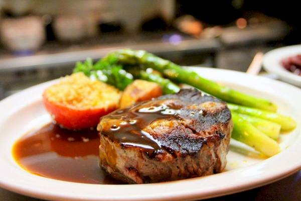 Ein Teller mit einem gebratenen Steak, Gemüse und Sauce.