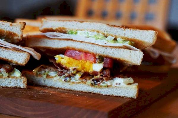 Nahaufnahme eines Sandwiches mit Ei und Bacon auf einem Holzbrett
