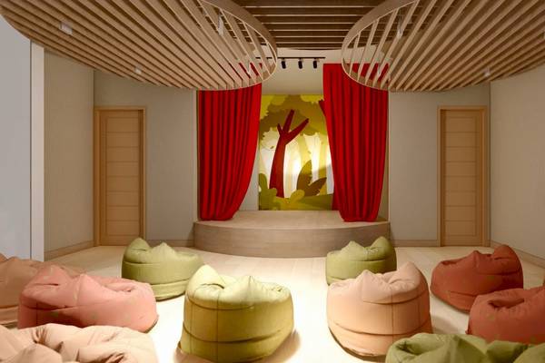 Innenansicht eines Theaters mit roten Vorhängen, Bühne und farbigen Bean Bags.