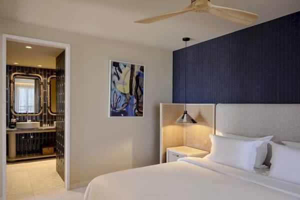Schlafzimmer im Atlantica Kalliston Resort mit einem großen Bett, weißen Kissen und einer modernen Wanddekoration.