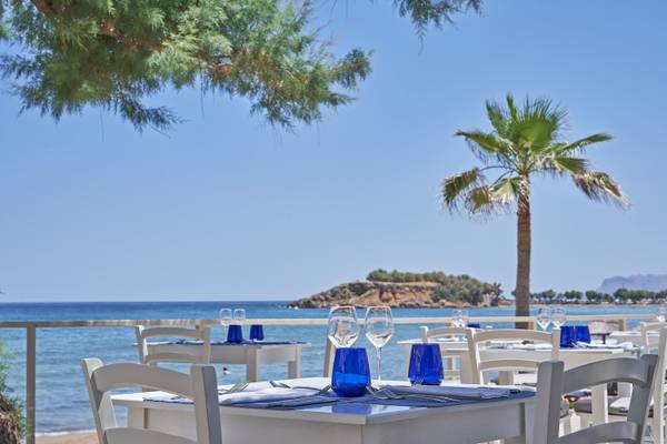 Terrasse des Atlantica Kalliston Resorts mit Tischen und Blick auf das Meer.