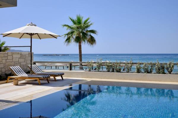 Pool-Terrasse des Atlantica Kalliston Resorts mit Blick auf das Meer und Sonnenschirmen.