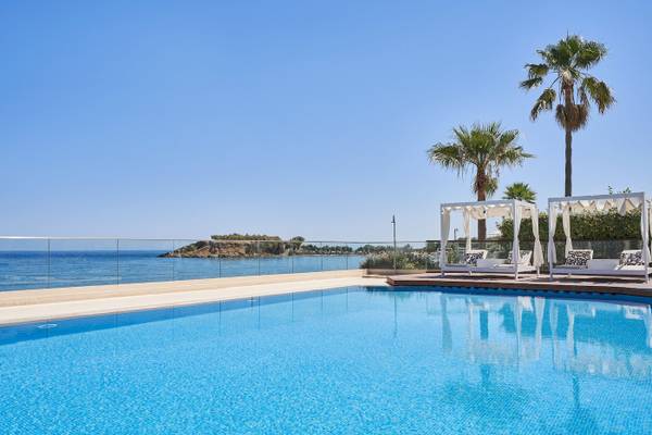 Ein Swimmingpool im Atlantica Kalliston Resort mit Liegen und Blick auf das Meer