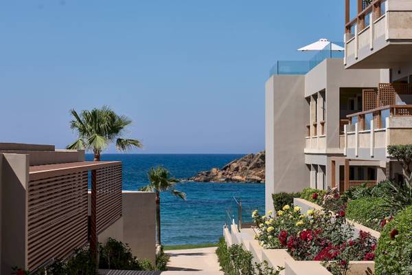 Außenansicht des Atlantica Kalliston Resorts mit Blick auf das Meer und eine Terrasse mit Sonnenschirm.
