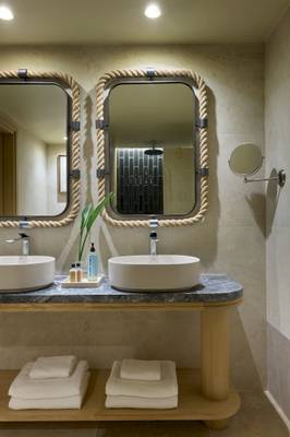 Badezimmer des Atlantica Kalliston Resorts mit zwei Waschbecken und Spiegeln.