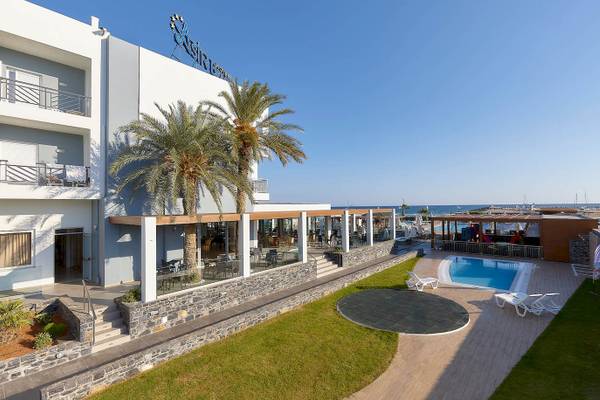 Außenansicht des Astir Beach Hotels auf Kreta mit Swimmingpool, Palmen und Terrasse.