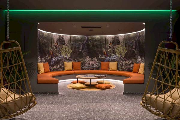 Loungebereich im Arminda Hotel & Spa mit geschwungenem Sofa und tropischem Wandbild.