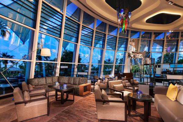 Innenansicht der Lobby des Jumeirah Beach Hotels mit großen Fenstern, modernen Möbeln und einem hängenden Kronleuchter.