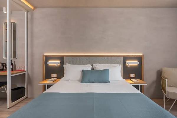 Schlafzimmer im Corissia Beach Hotel mit Bett, Kopfteilbeleuchtung und Nachttischen.