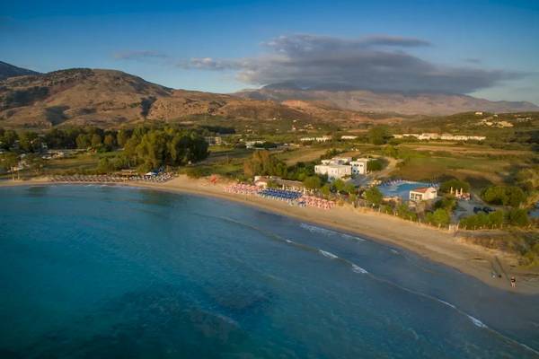 Luftaufnahme des Corissia Beach Hotels mit Strand, Swimmingpool und Bergen im Hintergrund.