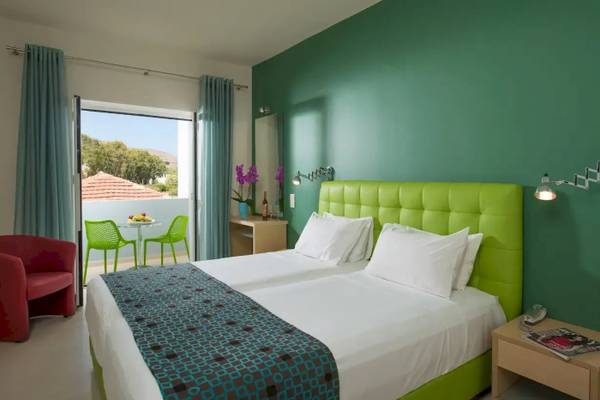 Doppelzimmer im Corissia Beach Hotel mit grüner Wand und Balkon.