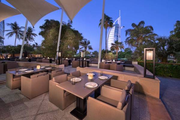 Außenbereich der Terrasse im Jumeirah Beach Hotel mit Tischen und Stühlen bei Dämmerung