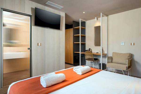 Innenansicht eines Zimmers im Corissia Beach Hotel mit Bett, Fernseher, Schreibtisch und Möbeln.