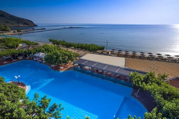 Luftaufnahme des Corissia Beach Hotels mit großem Swimmingpool, umgeben von Bäumen und Blick auf das Meer.