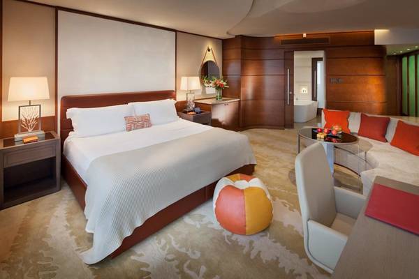 Schlafzimmer im Jumeirah Beach Hotel mit einem großen Bett, Nachttischen und einem Wohnzimmerbereich.
