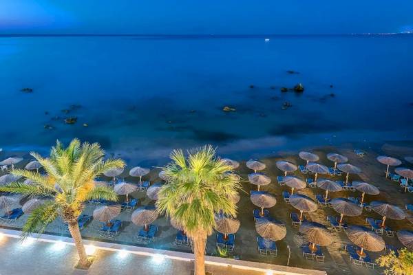 Abendblick auf den Strand des Corissia Beach Hotels mit vielen Sonnenschirmen und Liegen.