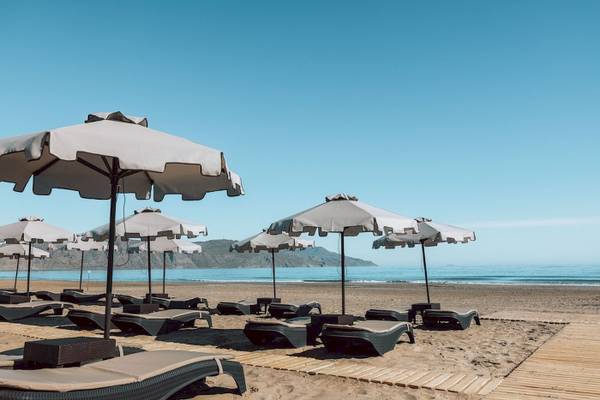 Eine Reihe von Sonnenliegen mit Sonnenschirmen auf dem Strand des Eliros Mare Hotels