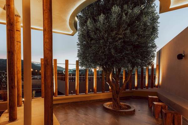 Außenterrasse des Eliros Mare Hotels mit einem großen Baum und hölzernen Stützen