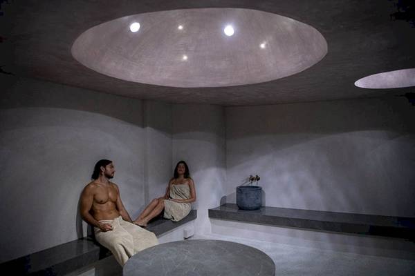 Sauna-Raum im Cretan Dream Resort & Spa mit einem Mann und einer Frau, die auf Bänken sitzen.